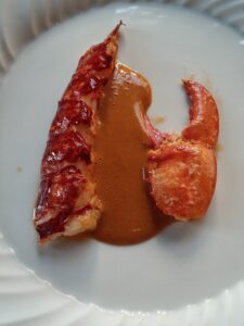 Blue Lobster from Brittany cooked in coral butter. Served with lobster ravioli and bouillabaisse.